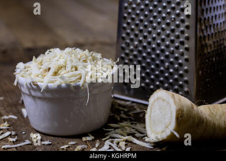 Racine de persil racine sur la grille et le persil. râpe sur la vieille table de cuisine dans la cuisine. fond noir Banque D'Images