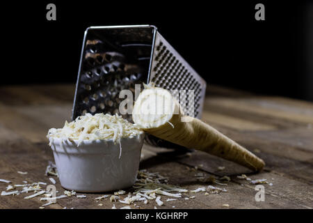 Racine de persil racine sur la grille et le persil. râpe sur la vieille table de cuisine dans la cuisine. fond noir Banque D'Images