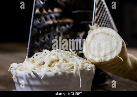 Racine de persil racine sur la grille et le persil. râpe sur la vieille table de cuisine dans la cuisine. fond noir Banque D'Images