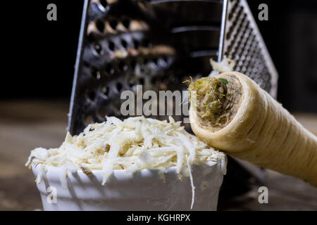 Racine de persil racine sur la grille et le persil. râpe sur la vieille table de cuisine dans la cuisine. fond noir Banque D'Images