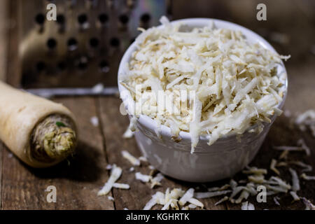 Racine de persil racine sur la grille et le persil. râpe sur la vieille table de cuisine dans la cuisine. fond noir Banque D'Images