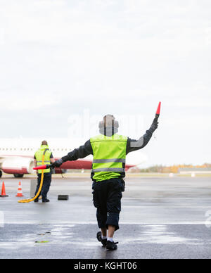 Le personnel au sol à la signalisation d'avion contre le ciel Banque D'Images