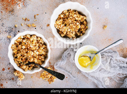 Le muesli avec du miel dans un bol et sur une table Banque D'Images