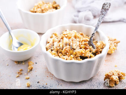 Le muesli avec du miel dans un bol et sur une table Banque D'Images