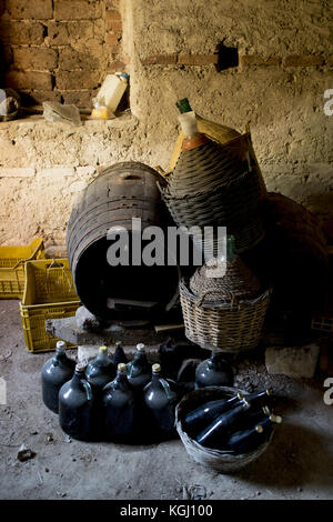 Cave à vin souterraine avec des bouteilles de vin , des fûts en bois et paille vieux-jeannes couvertes Banque D'Images