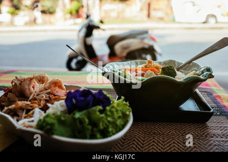 Deux plaques de spicy Thai Food sur la véranda sur la rue. Moto à l'arrière-plan. Banque D'Images