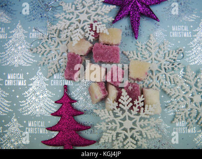 Photographie de nourriture de Noël traditionnel anglais de glace coco rose et blanc les sucreries les paillettes décorations et flocons sur capot table saisonniers Banque D'Images