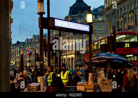 Les hommes de la distribution standard du soir de Noël à l'extérieur les clients de la station de métro Oxford Circus Banque D'Images