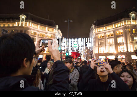 The West End, Londres, Royaume-Uni. 7 novembre 2017. Les magasins du West End de Londres se sont mis en route pour la saison de Noël, le soir, les lumières d'Oxford Street sont allumées. Les touristes prennent des photos de la lumière dans un Oxford Circus bondé. Crédit : Malcolm Park/Alay Live News. Banque D'Images