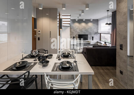 Appartement moderne avec table blanche et vaisselle noire Banque D'Images