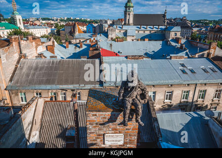 Statue de balai de cheminée sur le toit du célèbre restaurant House of Legends sur la vieille ville de Lviv, Ukraine. Ancienne église et monastère Bernardine sur b Banque D'Images