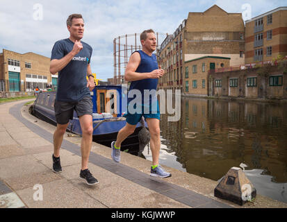 Deux jeunes hommes courir ensemble jogging le long du chemin de halage par le Regent's Canal à Hackney, East London, UK Banque D'Images