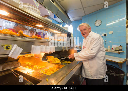 Homme âgé travaillant dans un style anglais traditionnel poisson et chip shop, UK Banque D'Images