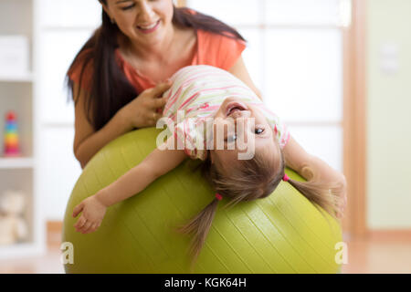 Cute child girl stretching sur pilates fitness ball avec la mère dans la salle de sport Banque D'Images