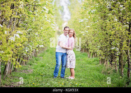 Couple standing in orchard à vers la caméra, serrant les uns les autres Banque D'Images