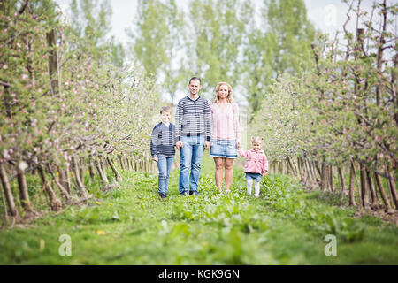 Heureux les jeunes quatre états family Standing together outdoors in orchard Banque D'Images