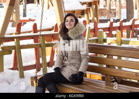 Jeune femme en hiver, assis sur un banc de parc Banque D'Images