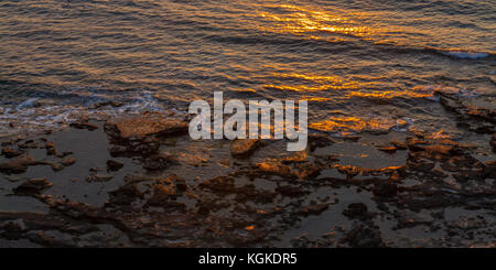 Rocky seashore et réflexions du soleil au coucher du soleil. Tourné en pomos, région de Paphos, Chypre Banque D'Images