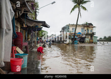 Un enfant joue sur le trottoir d'une rue inondée dans le centre historique de la vieille ville de Hoi An, Vietnam Banque D'Images