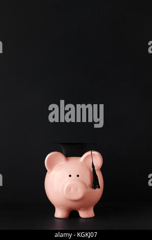 Les frais de scolarité en céramique avec concept pink piggy bank face à l'avant au niveau de l'oeil le port d'un mortier noir. Tableau noir fond avec copie espace ci-dessus. Banque D'Images