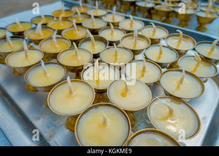 Close up de bougies à l'intérieur d'un ametallic gobelets d'or sur le bac d'une table en vue de l'extérieur à l'édifice stupa boudhanath à Katmandou, Népal Banque D'Images