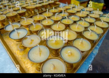 Close up de bougies à l'intérieur d'un ametallic gobelets d'or sur le bac d'une table en vue de l'extérieur à l'édifice stupa boudhanath à Katmandou, Népal Banque D'Images