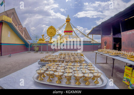 KATMANDOU, NÉPAL 15 OCTOBRE 2017 : gros plan de bougies à l'intérieur d'un gobelet doré au-dessus d'un plateau amétallique dans une table avec une vue du bâtiment Boudhanath Stupa à l'extérieur à Katmandou, Népal Banque D'Images