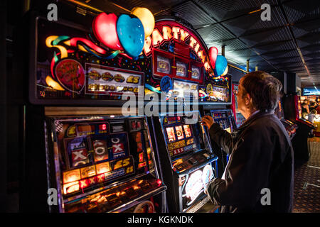 Un homme jouant sur une «Party Time» une machine à fruits bandit armé ou machine à sous dans une salle de jeux d'arcade Royaume-Uni Banque D'Images