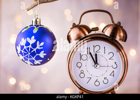 Le cuivre vintage réveil montrant cinq minutes à minuit. new year countdown. Blue Christmas Tree ball with sunglasses sur branch. brillante Banque D'Images