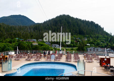 Le pont arrière du navire de croisière Eurodam montrant une piscine et de chaises longues et donnant sur de magnifiques collines boisées où les maisons sont nichées. Banque D'Images