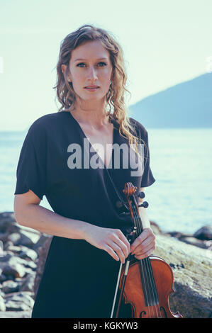 Portrait of Beautiful woman holding violin debout au Lakeshore Banque D'Images