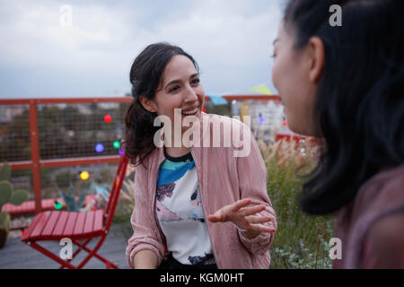 Happy Woman talking to female friend while sitting on patio Banque D'Images