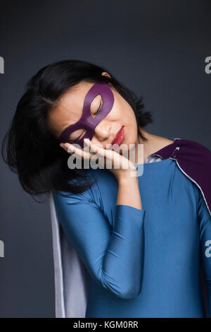 La sieste du super-héros féminin contre l'arrière-plan gris Banque D'Images