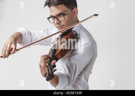 Certain young man playing violin against white background Banque D'Images