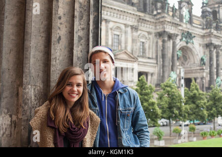 Portrait of smiling young friends standing par colonne à l'Altes Museum à l'encontre de la cathédrale de Berlin Banque D'Images