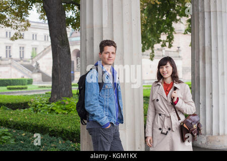 Portrait of smiling young friends standing par colonne, Berlin, Allemagne Banque D'Images