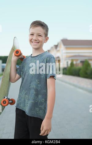 Portrait of smiling boy holding skateboard en se tenant sur le street Banque D'Images