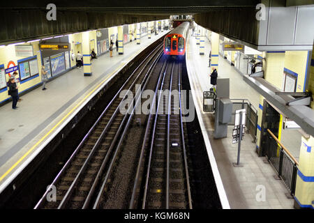 Une rame de métro à la plate-forme de la station Aldgate East sur le système de métro de Londres avec les usagers en attente Banque D'Images