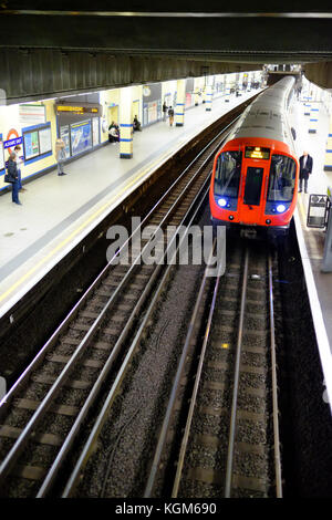 Une rame de métro à la plate-forme de la station Aldgate East sur le système de métro de Londres avec les usagers en attente Banque D'Images