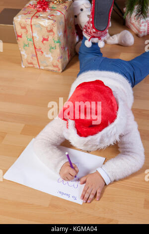 Petite fille de préparer la lettre de Santa. Elle peint une feuille avec en-tête en anglais Banque D'Images