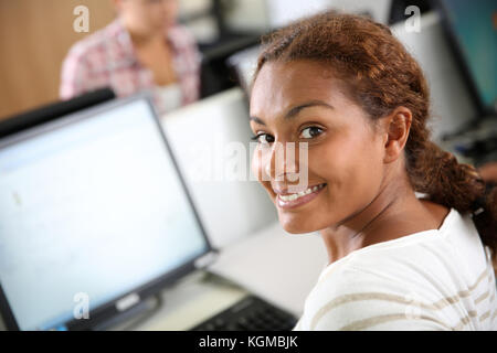 Smiling little girl sitting in front of desktop Banque D'Images