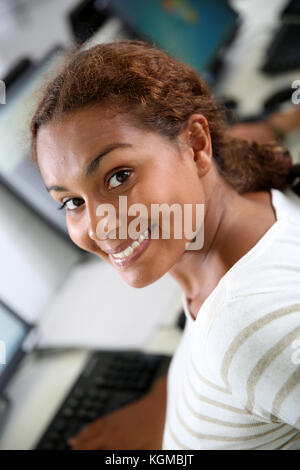 Smiling little girl sitting in front of desktop Banque D'Images