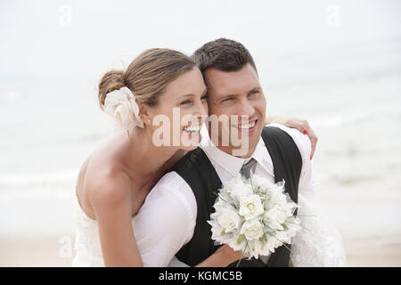 Groom donner piggyback ride à bride sur la plage Banque D'Images