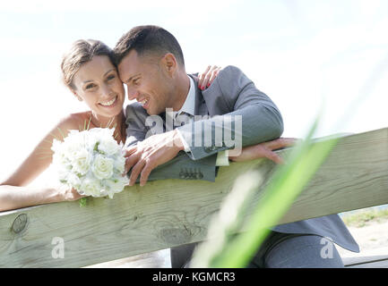 Portrait of Bride and Groom leaning on fence Banque D'Images