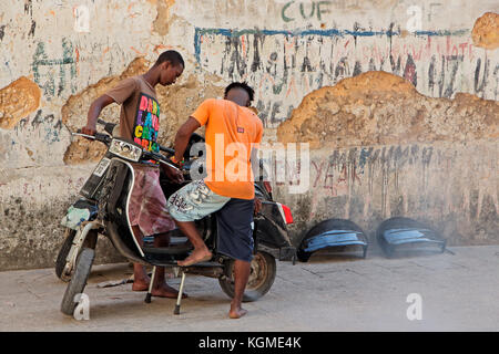 Stone Town, Zanzibar, Tanzanie - le 29 octobre 2014 : hommes non identifiés travaillant sur un scooter (moto) dans une ruelle étroite de la ville en pierre historique Banque D'Images