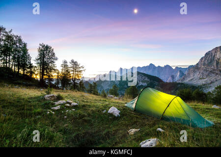 Une tente s'allume sous un ciel de nuit de lune au crépuscule, heure. Alpes, Parc national du Triglav, en Slovénie. Banque D'Images