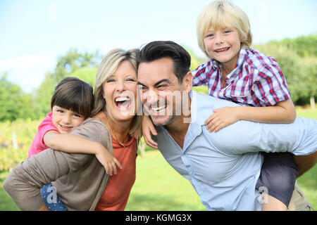 Les parents qui piggyback ride to kids in park Banque D'Images