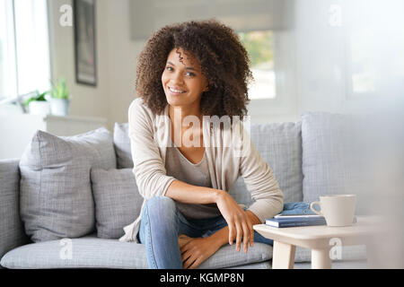 Beuatiful mixed race woman relaxing in canapé Banque D'Images