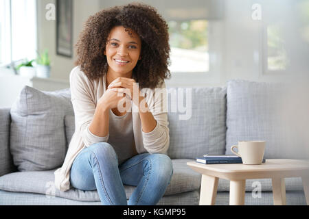 Beuatiful mixed race woman relaxing in canapé Banque D'Images