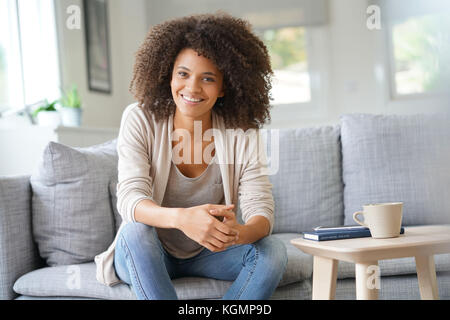 Beuatiful mixed race woman relaxing in canapé Banque D'Images